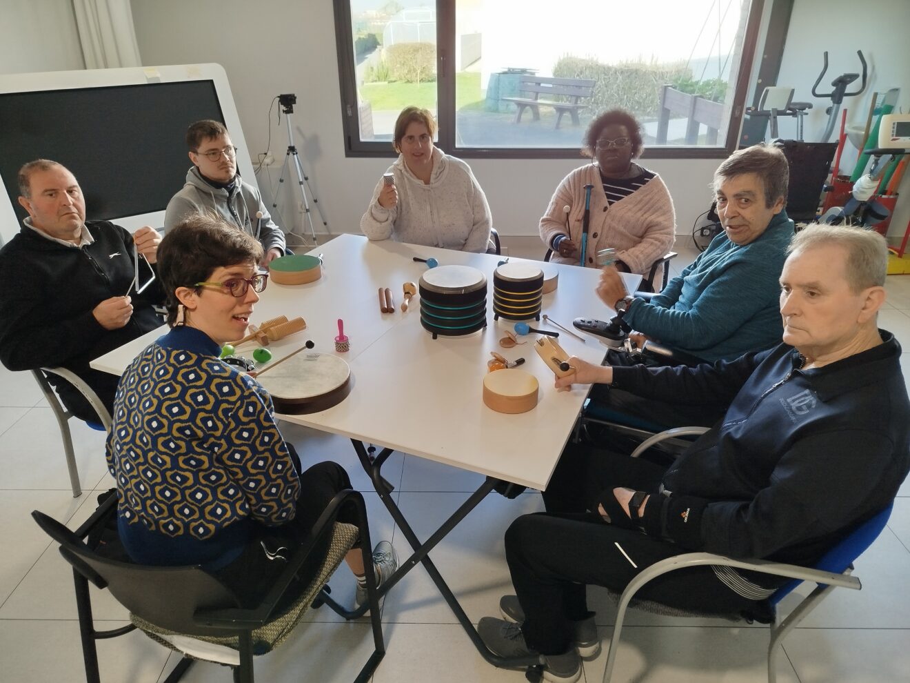 En la foto se ve a varias personas usuarias de Adacen alrededor de una mesa en la que hay varios instrumentos musicales