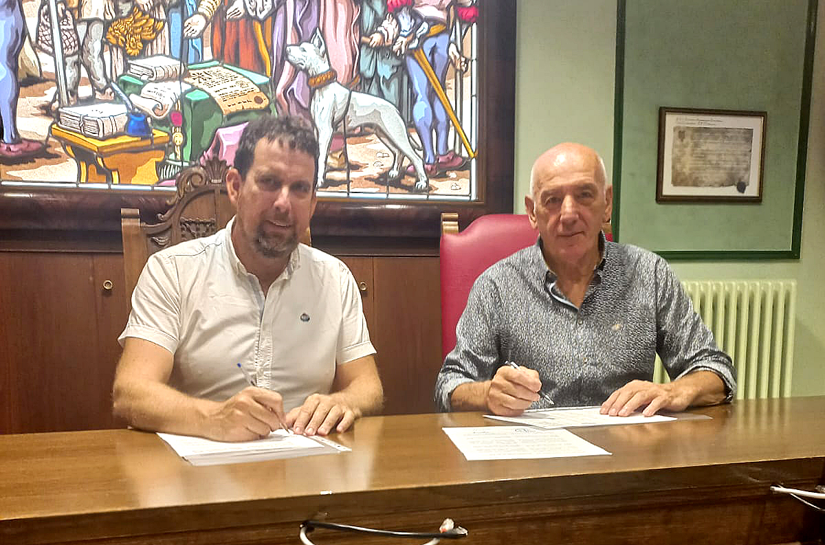En la imagen se ve al presidente de Adacen y al alcalde de Villava sentados en una mesa del salón de plenos firmando el convenio.