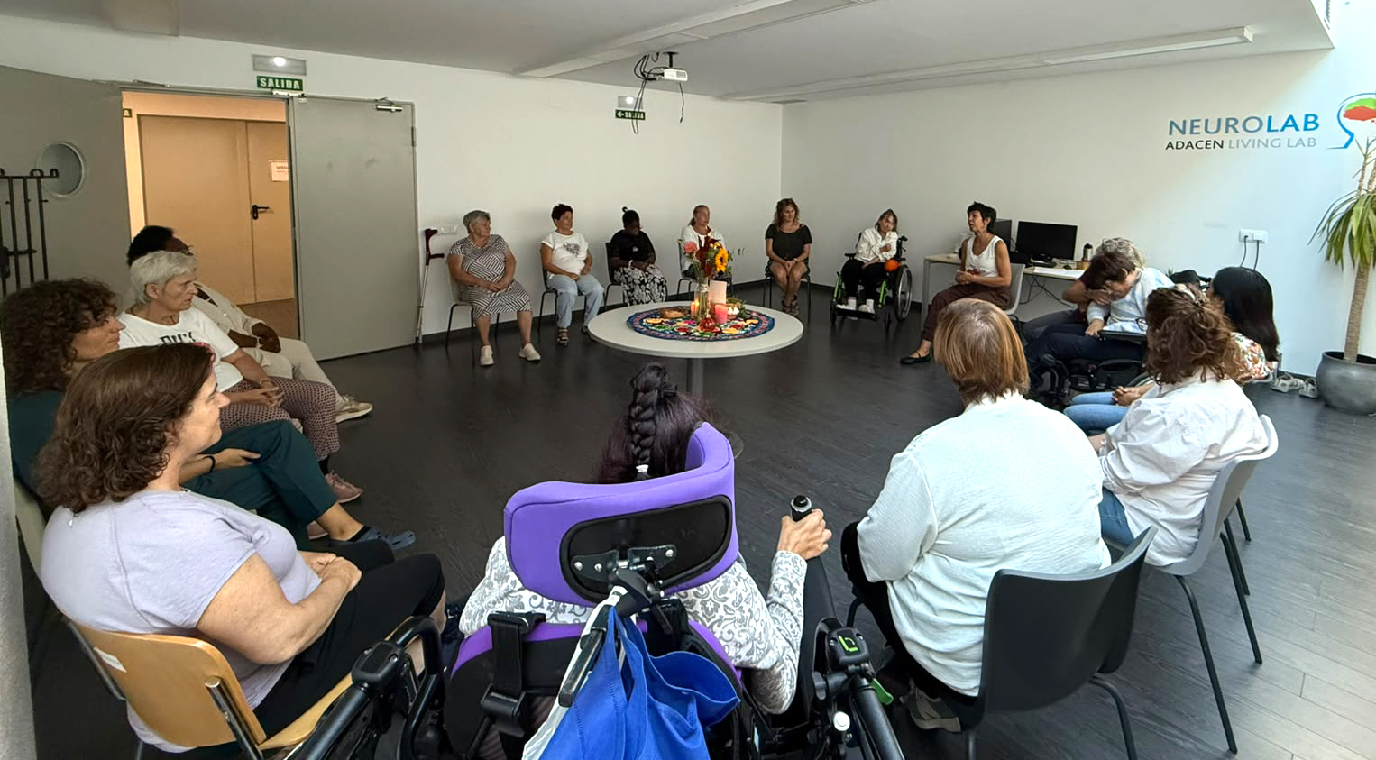 En la imagen se ve a mujeres de Adacen sentadas en círculo atendiendo a las explicaciones de otra mujer que se sitúa en el centro